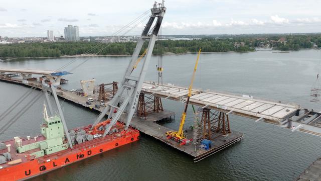 suuri laivanosturi nostaa siltaelementtiä rakenteilla olevaan kruunuvuorensiltaan. silta on vielä kesken.