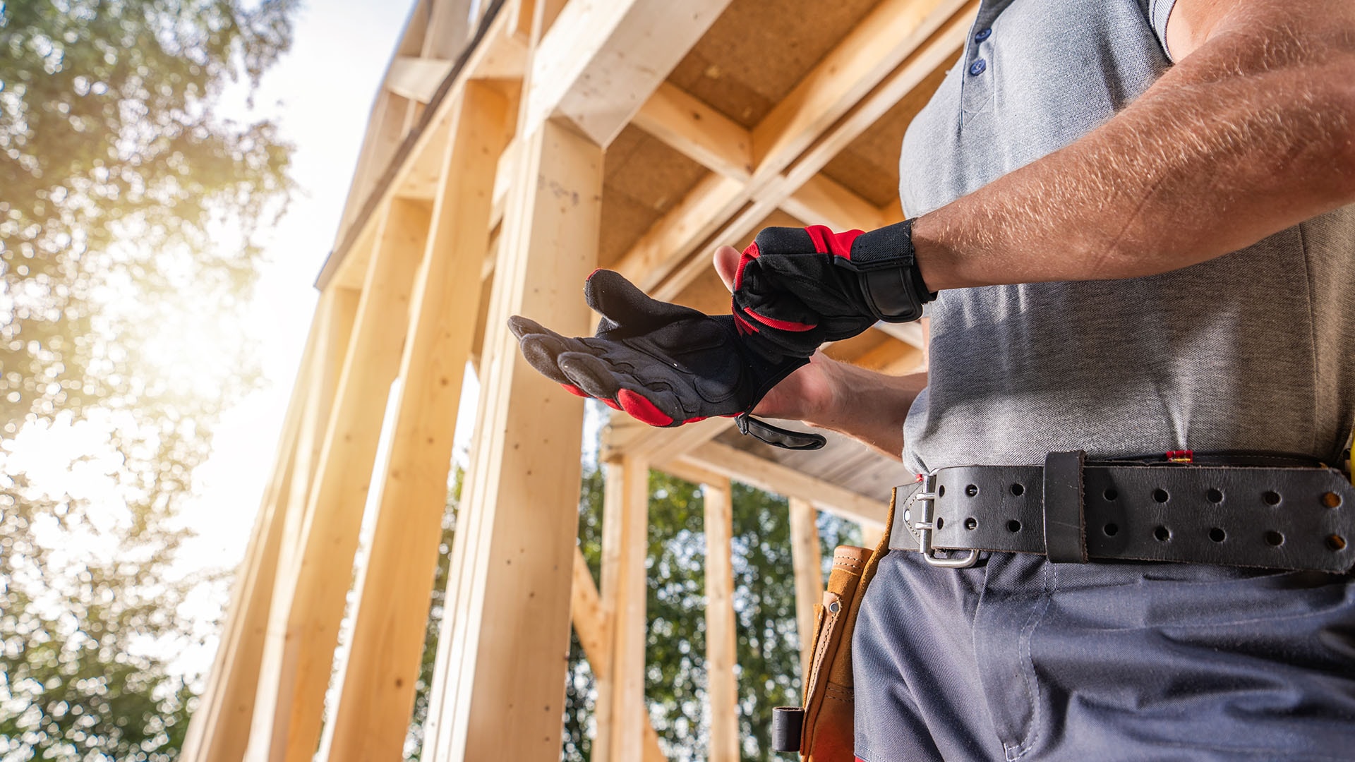 1920 kirvesmies seisoo rakennustyömaalla ja laittaa työhanskaa takaisin käteensä