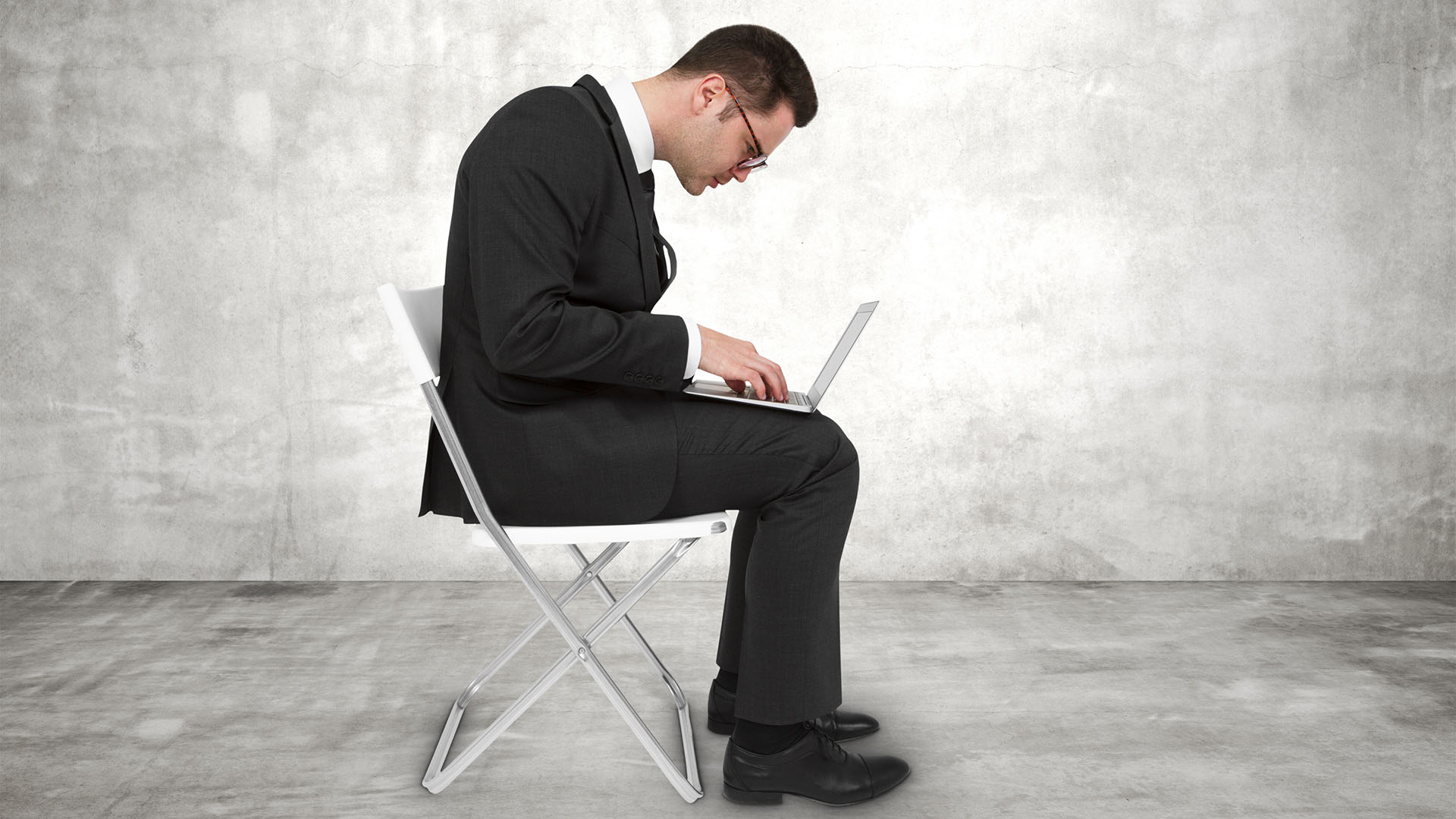 1920 mies puvussa kannettava tietokone sylissä