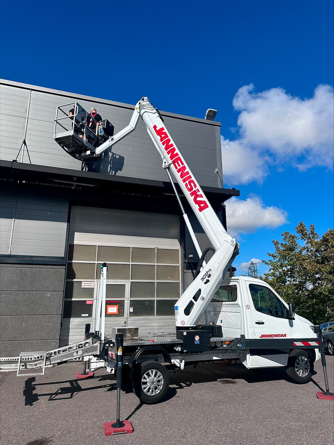 nostolava-auto puomi ylhäällä ja mies töissä korkealla korissa