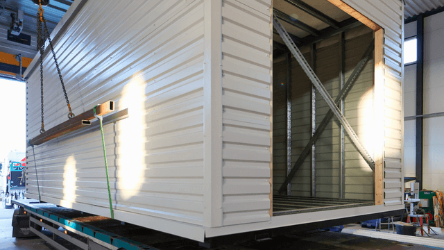 rakennusmoduuli lähdössä tehtaalta ja sitä nostetaan rekan kyytiin